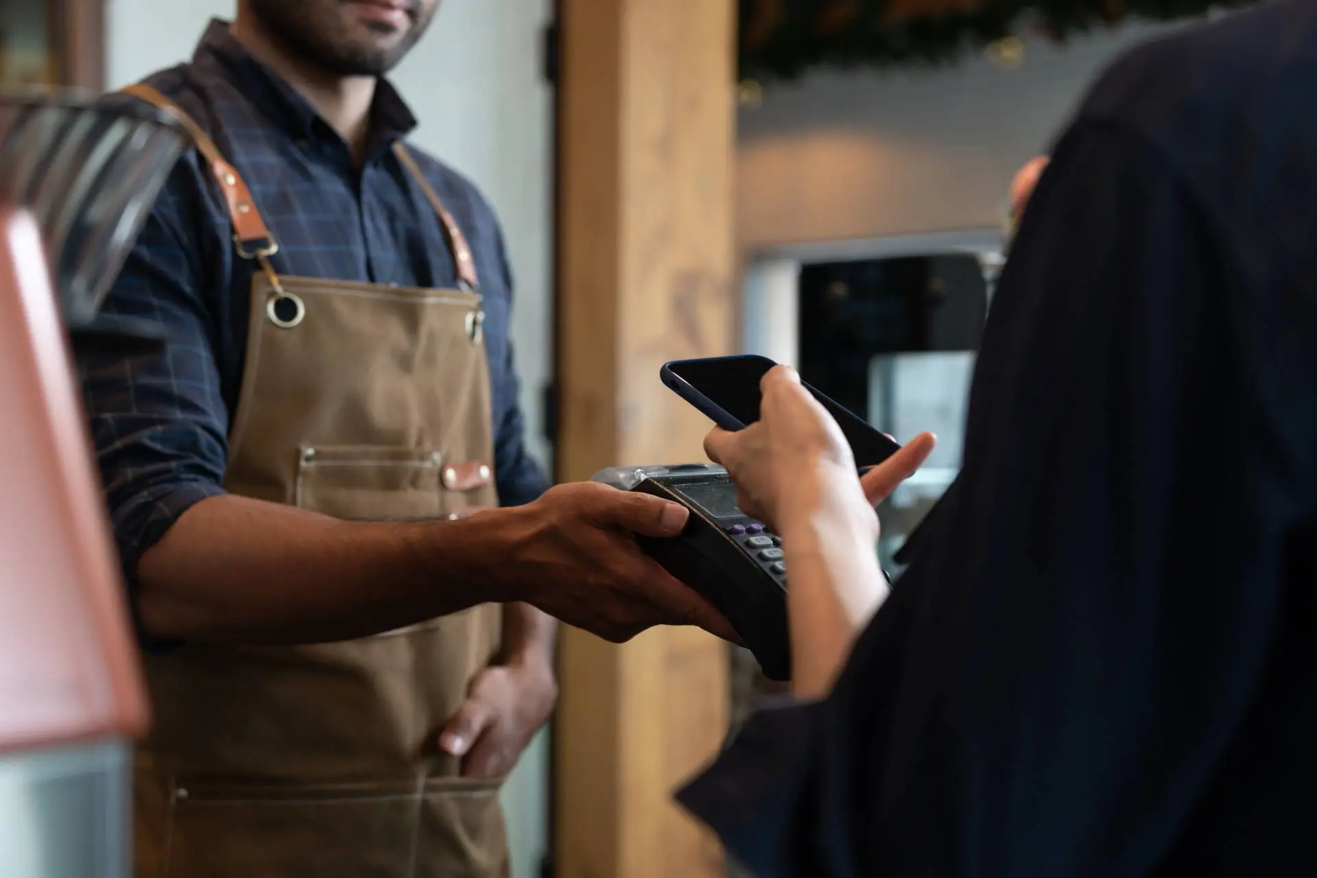 shop owner accepting payments from mobile wallet with pos machine