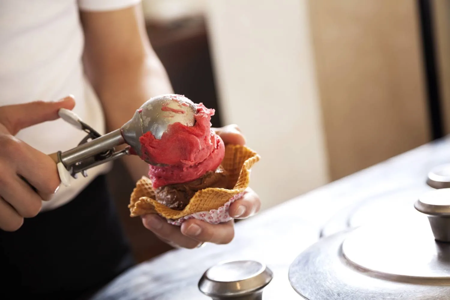 gelateria worker serving ice cream gelato in waffle wafer bowl